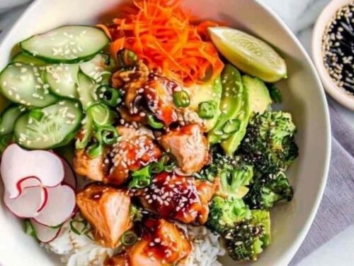 Crispy salmon bowls with glazed soy honey salmon, sushi rice, avocado, cucumber, and sesame seeds in white bowls