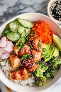 Crispy salmon bowls with glazed soy honey salmon, sushi rice, avocado, cucumber, and sesame seeds in white bowls