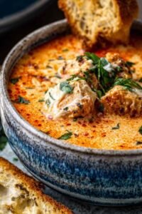 Crock Pot Creamy Chicken Parmesan Soup served in a white bowl topped with fresh basil and grated Parmesan