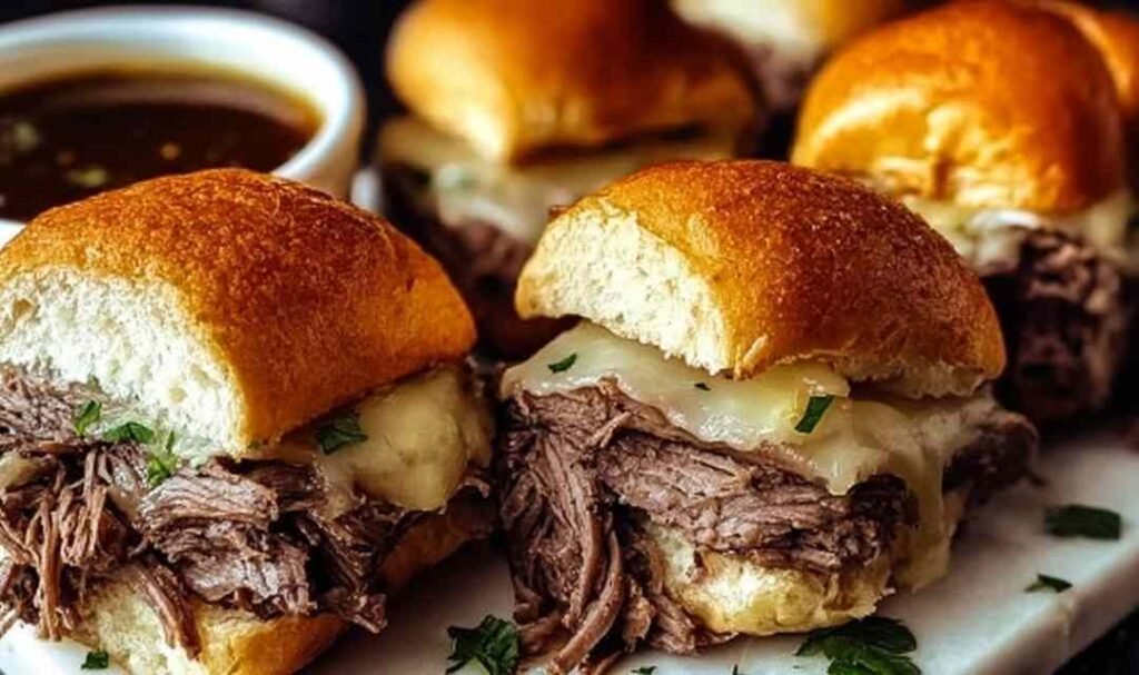 Crock Pot French Dip Sandwich with shredded beef and melted provolone cheese on a toasted hoagie roll served with a bowl of au jus for dipping