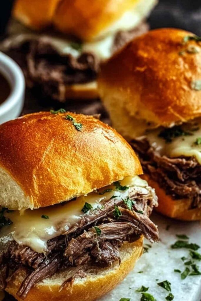 Crock Pot French Dip Sandwich with shredded beef and melted provolone cheese on a toasted hoagie roll served with a bowl of au jus for dipping