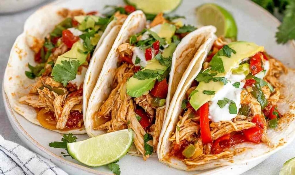 Crockpot chicken fajitas with juicy shredded chicken, red and yellow bell peppers, and onions in a slow cooker