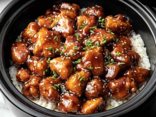 Crockpot General Tso's Chicken served over steamed white rice topped with sesame seeds and green onions