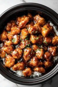 Crockpot General Tso's Chicken served over steamed white rice topped with sesame seeds and green onions