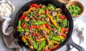 Easy vegetable stir fry with broccoli, bell peppers, snap peas, and mushrooms in a ginger garlic sauce in a large wok