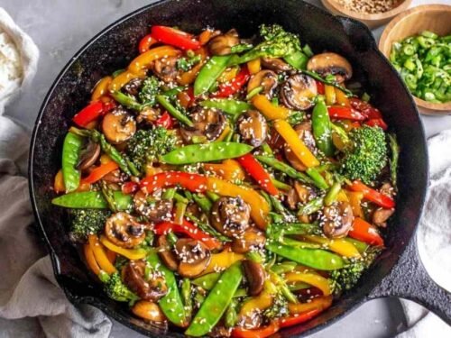 Easy vegetable stir fry with broccoli, bell peppers, snap peas, and mushrooms in a ginger garlic sauce in a large wok