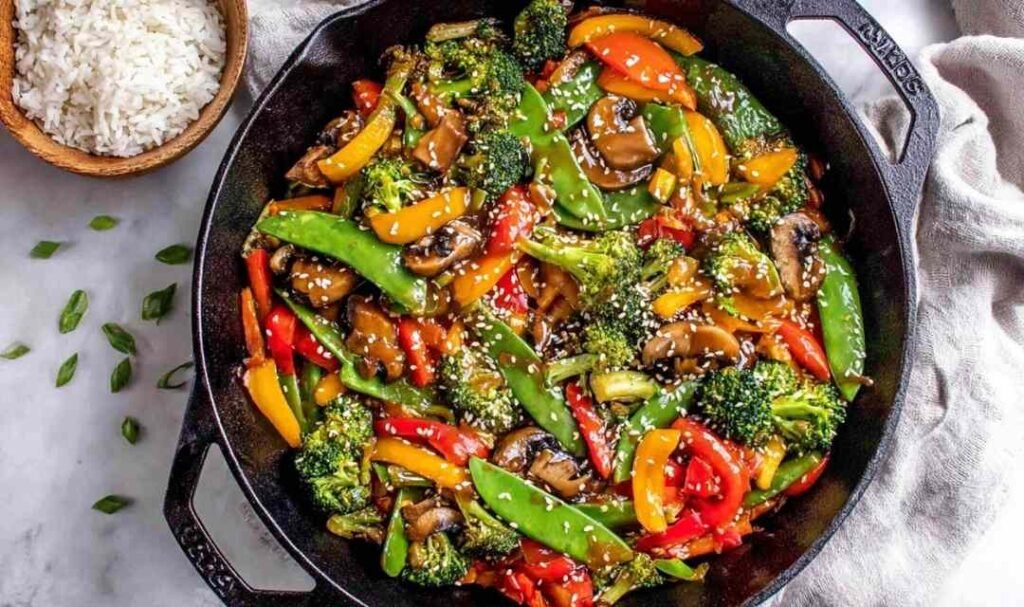 Easy vegetable stir fry with broccoli, bell peppers, snap peas, and mushrooms in a ginger garlic sauce in a large wok