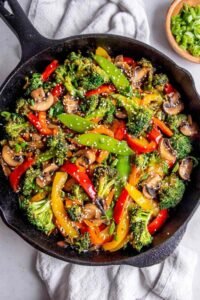 Easy vegetable stir fry with broccoli, bell peppers, snap peas, and mushrooms in a ginger garlic sauce in a large wok