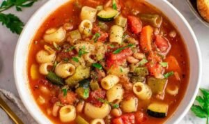 Bowl of minestrone soup with vegetables, beans, and pasta topped with Parmesan cheese
