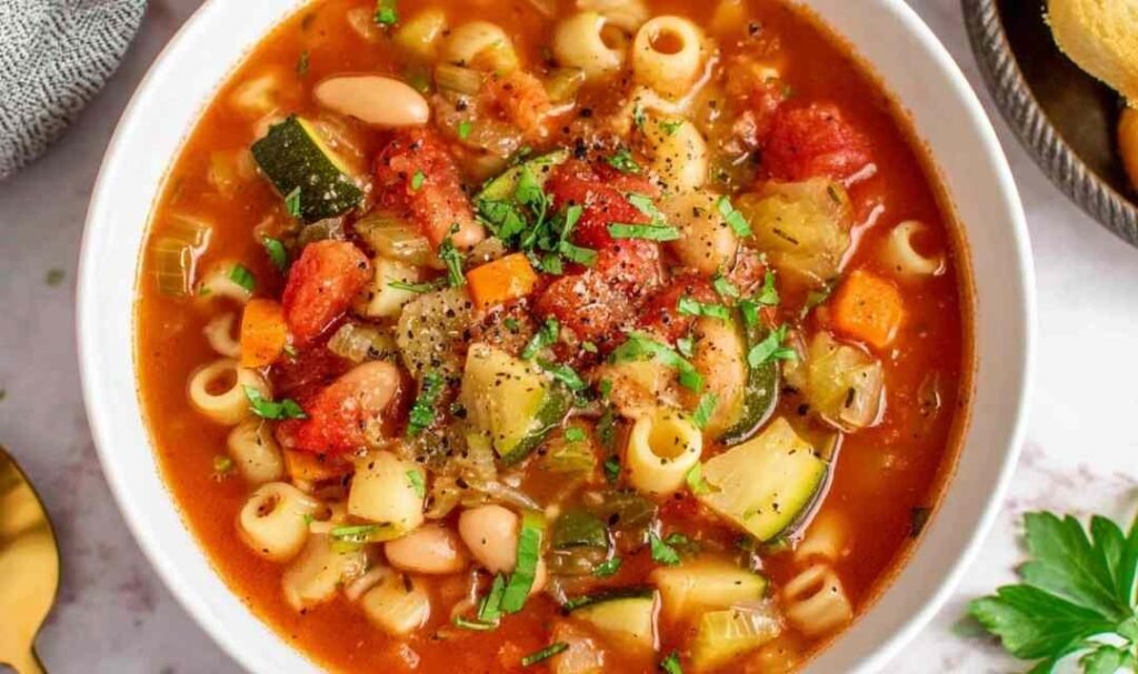 Bowl of minestrone soup with vegetables, beans, and pasta topped with Parmesan cheese