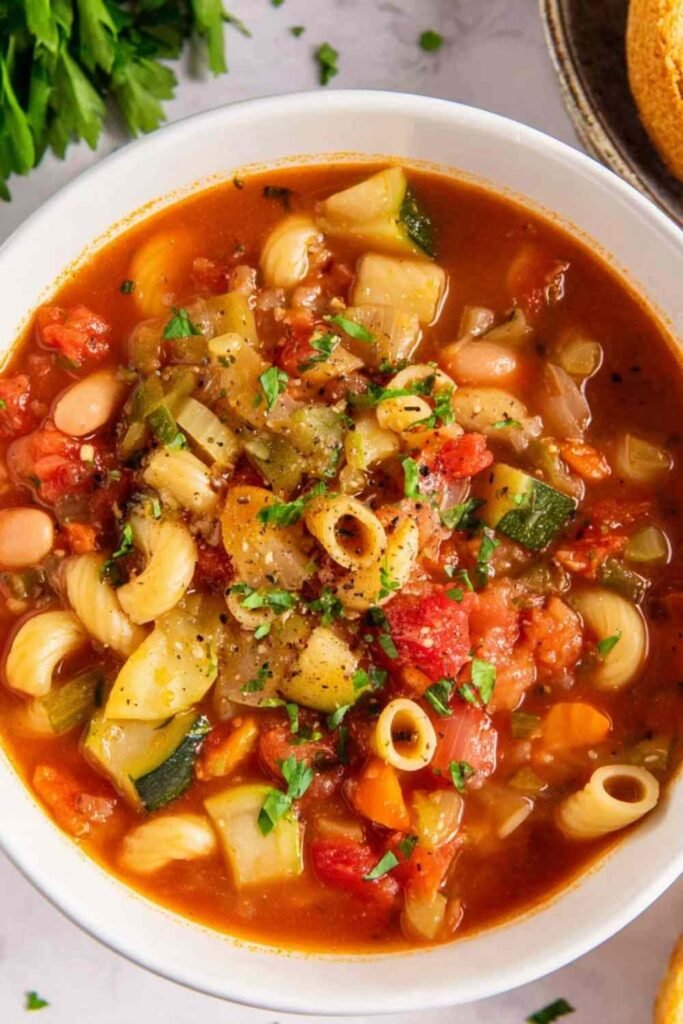 Bowl of minestrone soup with vegetables, beans, and pasta topped with Parmesan cheese