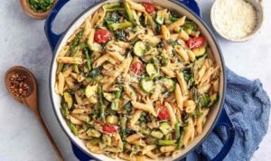 Colorful pasta primavera with broccoli, zucchini, cherry tomatoes, and Parmesan served in a white bowl