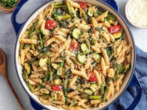 Colorful pasta primavera with broccoli, zucchini, cherry tomatoes, and Parmesan served in a white bowl