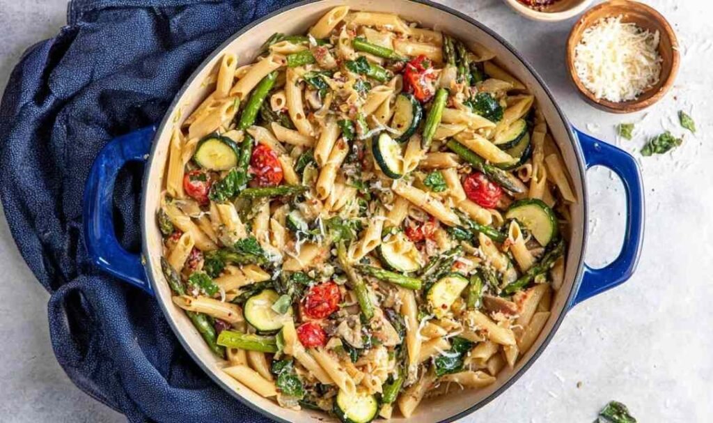 Colorful pasta primavera with broccoli, zucchini, cherry tomatoes, and Parmesan served in a white bowl