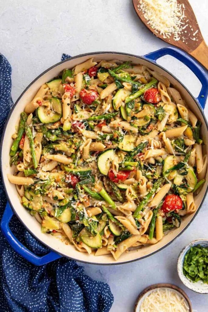 Colorful pasta primavera with broccoli, zucchini, cherry tomatoes, and Parmesan served in a white bowl