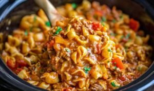 Bowl of slow cooker taco pasta with seasoned ground beef, shell pasta, cheddar cheese, sour cream, and fresh cilantro