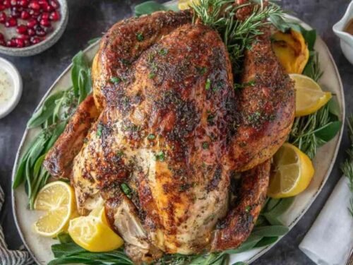 Whole turkey rubbed with homemade garlic herb butter in a roasting pan ready for the oven for this Thanksgiving turkey recipe