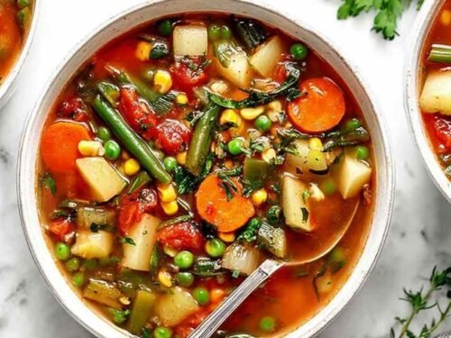 Bowl of easy vegetable soup with carrots, potatoes, green beans, and parsley on a rustic wooden table