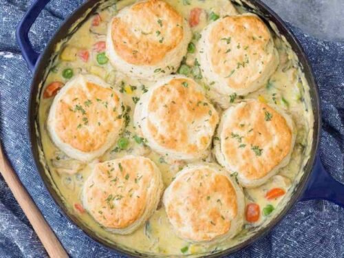 Chicken Pot Pie with Biscuits in a cast iron skillet fresh from the oven with golden brown biscuit tops and bubbly filling
