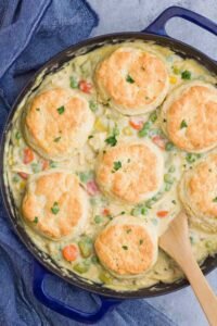 Chicken Pot Pie with Biscuits in a cast iron skillet fresh from the oven with golden brown biscuit tops and bubbly filling