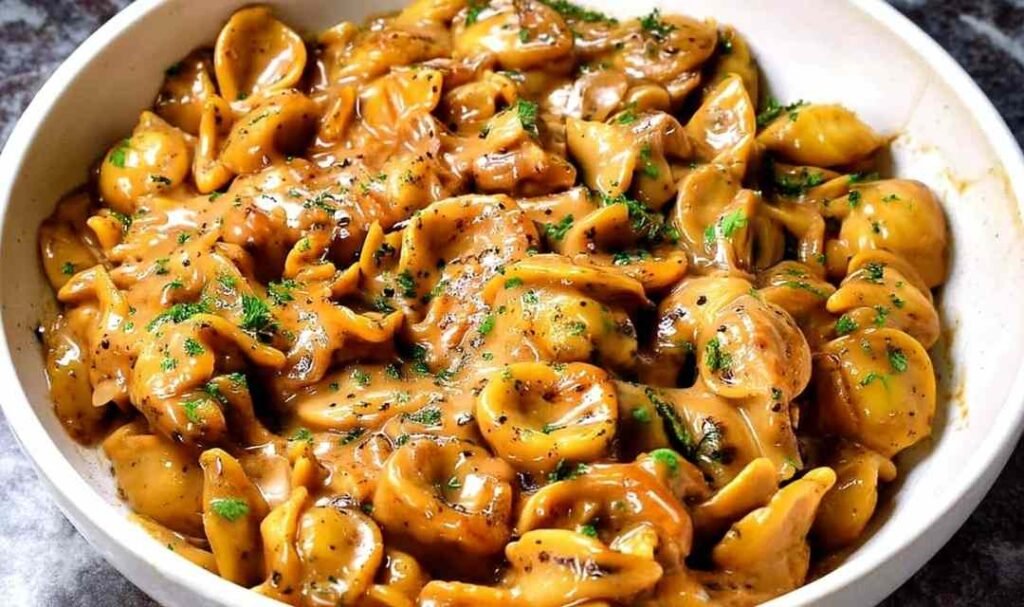 Creamy one pot French Onion Pasta topped with melted Gruyere and fresh parsley in a white bowl