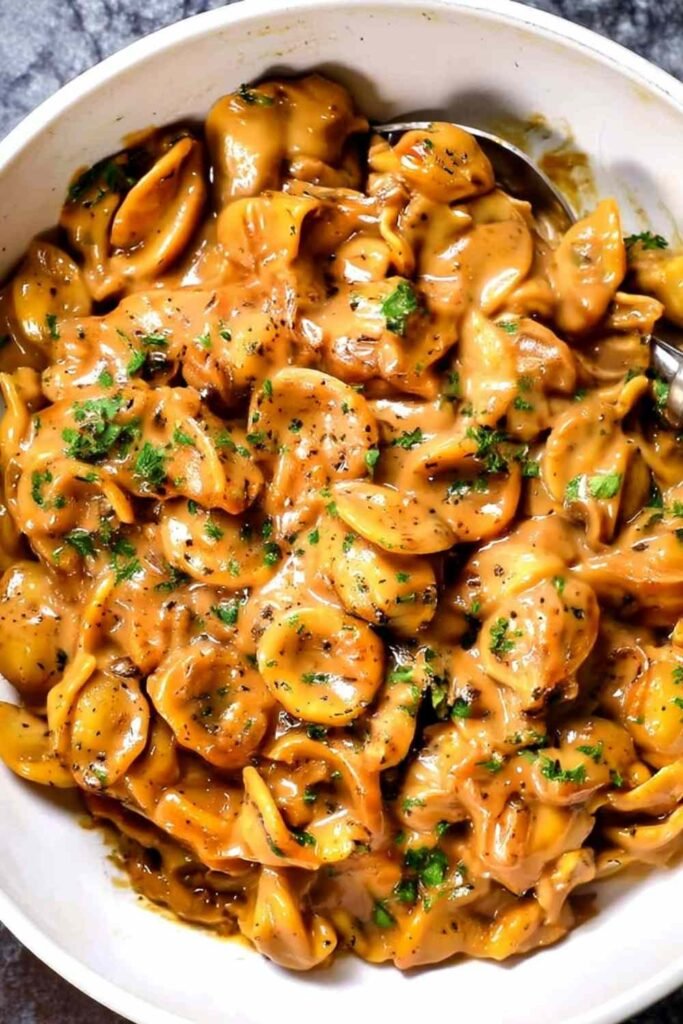 Creamy one pot French Onion Pasta topped with melted Gruyere and fresh parsley in a white bowl