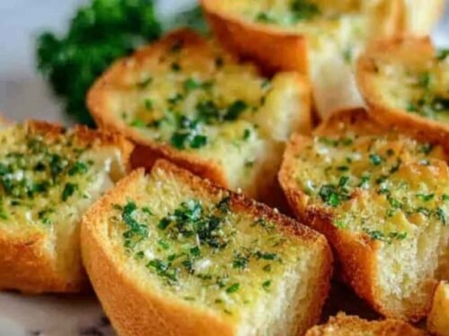 Crispy garlic bread with sliced bread on a baking sheet with golden buttery edges and fresh parsley