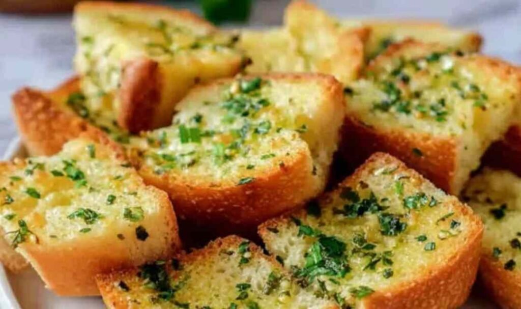Crispy garlic bread with sliced bread on a baking sheet with golden buttery edges and fresh parsley