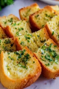 Crispy garlic bread with sliced bread on a baking sheet with golden buttery edges and fresh parsley