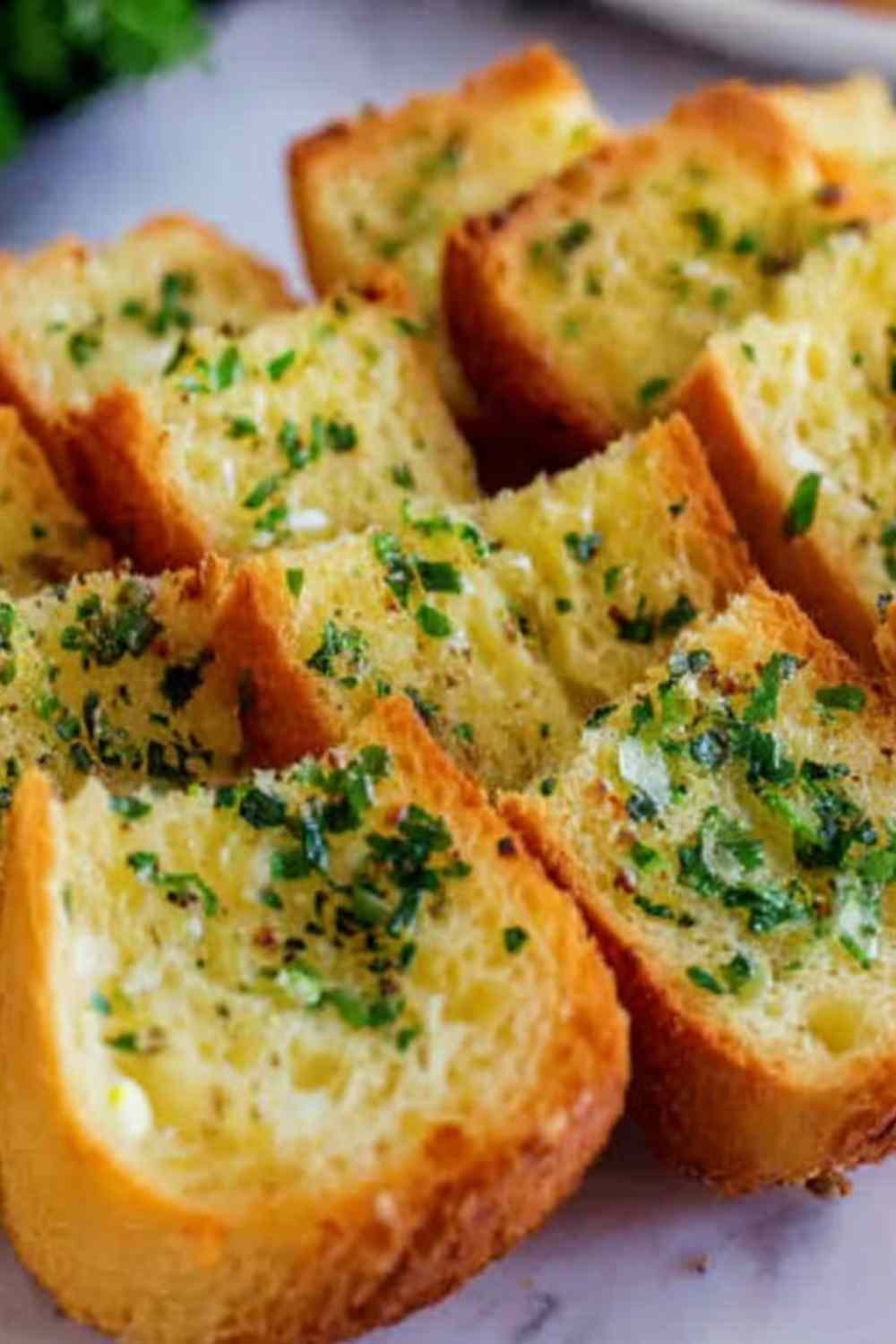Crispy garlic bread with sliced bread on a baking sheet with golden buttery edges and fresh parsley