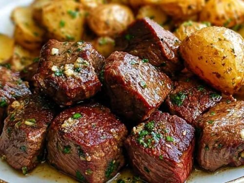 Garlic butter steak bites and crispy baby potatoes in a cast iron skillet garnished with fresh parsley