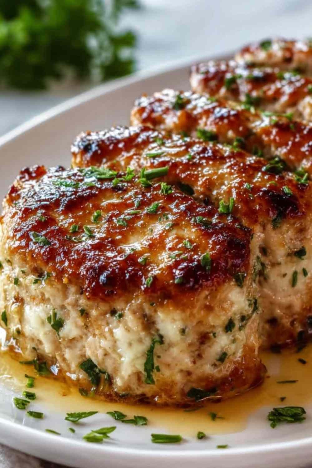 Sliced Garlic Parmesan Chicken Meatloaf on a white plate with golden Parmesan crust and fresh parsley garnish