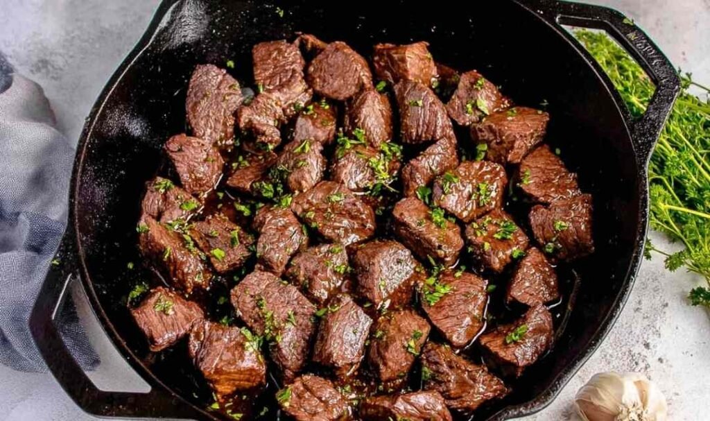 Juicy steak tips searing in a cast iron skillet with a golden brown crust and garlic soy marinade