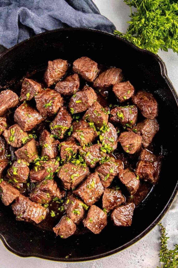 Juicy steak tips searing in a cast iron skillet with a golden brown crust and garlic soy marinade
