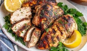 Juicy grilled chicken breasts cooked with Greek chicken marinade served with lemon slices and fresh herbs