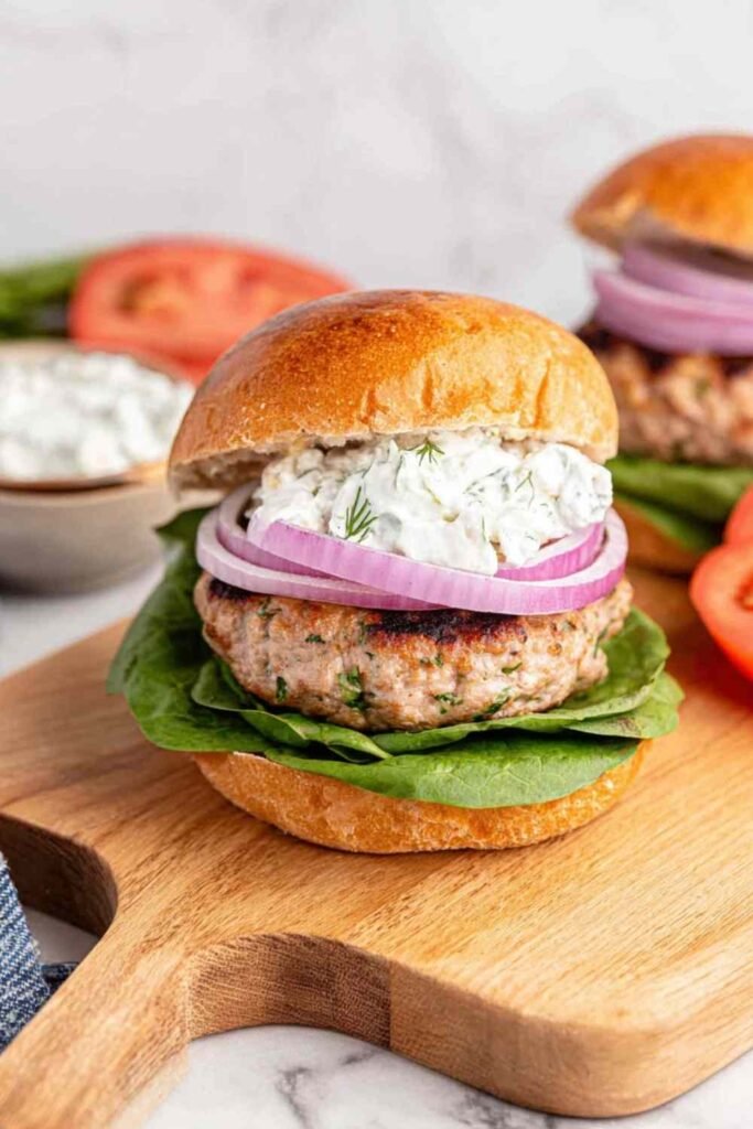Juicy Greek turkey burgers topped with tzatziki, lettuce, and tomato on toasted buns