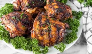Juicy grilled chicken thighs coated in brown sugar smoked paprika spice rub cooking on a hot grill with caramelized grill marks forming on the surface