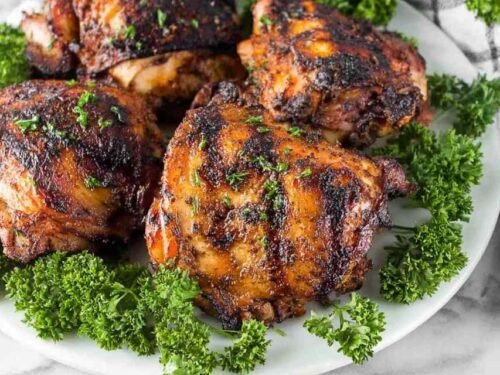Juicy grilled chicken thighs coated in brown sugar smoked paprika spice rub cooking on a hot grill with caramelized grill marks forming on the surface