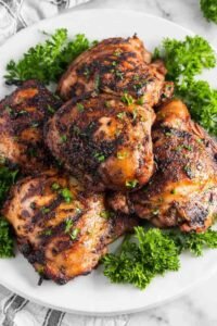 Juicy grilled chicken thighs coated in brown sugar smoked paprika spice rub cooking on a hot grill with caramelized grill marks forming on the surface