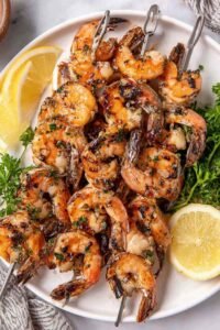 Juicy grilled shrimp on skewers cooking on a hot grill with golden char marks and garlic herb marinade