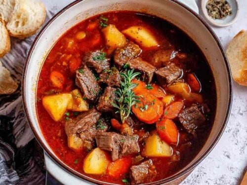 Easy beef stew recipe simmering in a Dutch oven with tender beef, carrots, and potatoes in a rich red wine broth