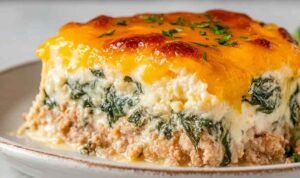 High protein ground turkey casserole golden and bubbly with melted cheddar in a white baking dish