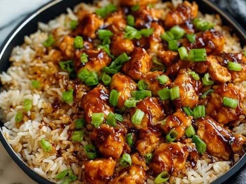 Honey BBQ chicken rice in a large skillet with golden chicken thighs, fluffy rice, and mixed vegetables garnished with chopped green onions