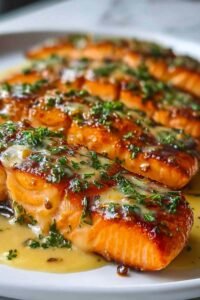 Honey garlic butter baked salmon fillets on a plate with caramelized glaze and lemon slices