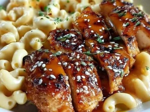 Honey pepper chicken mac and cheese served on a plate with sticky glazed chicken slices over creamy cheddar macaroni