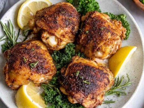 Juicy instant pot chicken thighs with golden seared skin served on a white plate with pan gravy and chopped parsley