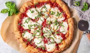 Classic margherita pizza with fresh mozzarella, San Marzano tomato sauce, and fresh basil on a golden crispy crust baked at home