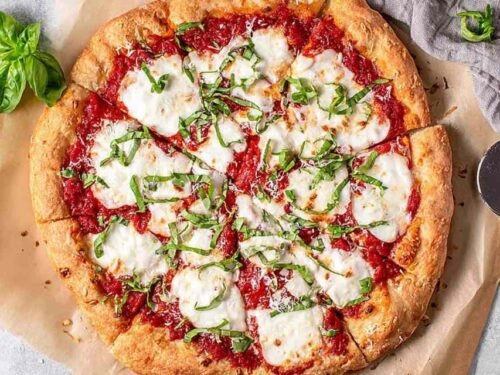 Classic margherita pizza with fresh mozzarella, San Marzano tomato sauce, and fresh basil on a golden crispy crust baked at home