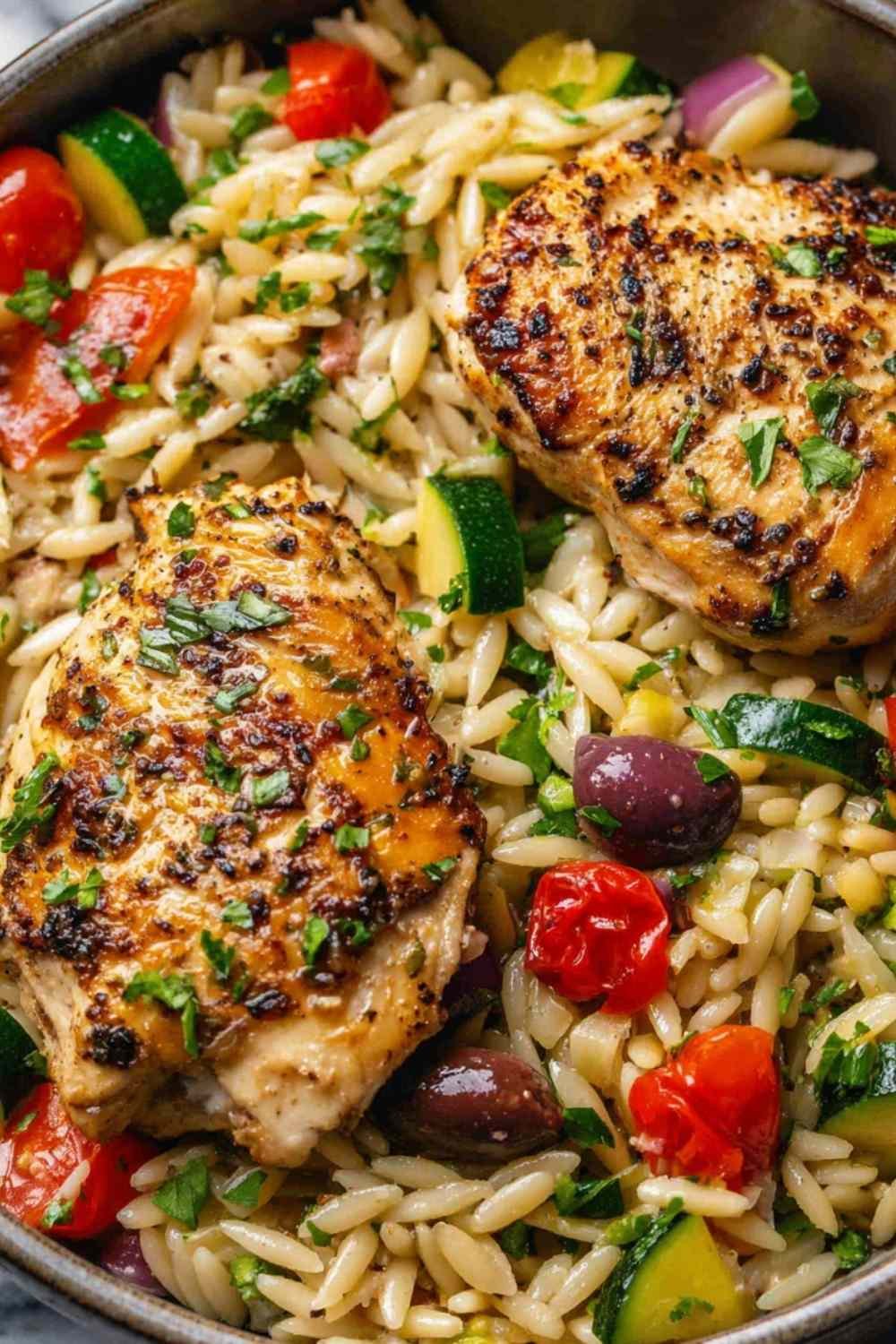 Mediterranean chicken orzo with sliced chicken, baby spinach, and sun-dried tomatoes in a large skillet
