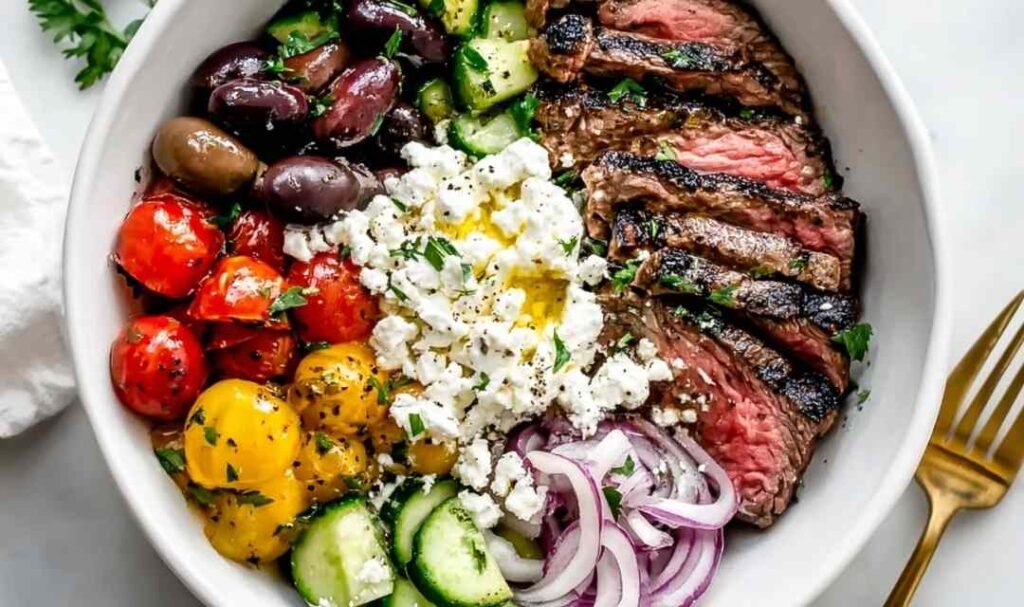 Mediterranean Steak Bowl with sliced grilled sirloin, cherry tomatoes, cucumber, kalamata olives, feta, and homemade tzatziki over brown rice